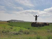 41-me_on_bale_of_hay_with_White_Butte_in_background-not_so_easy_to_hoist_up_bale
